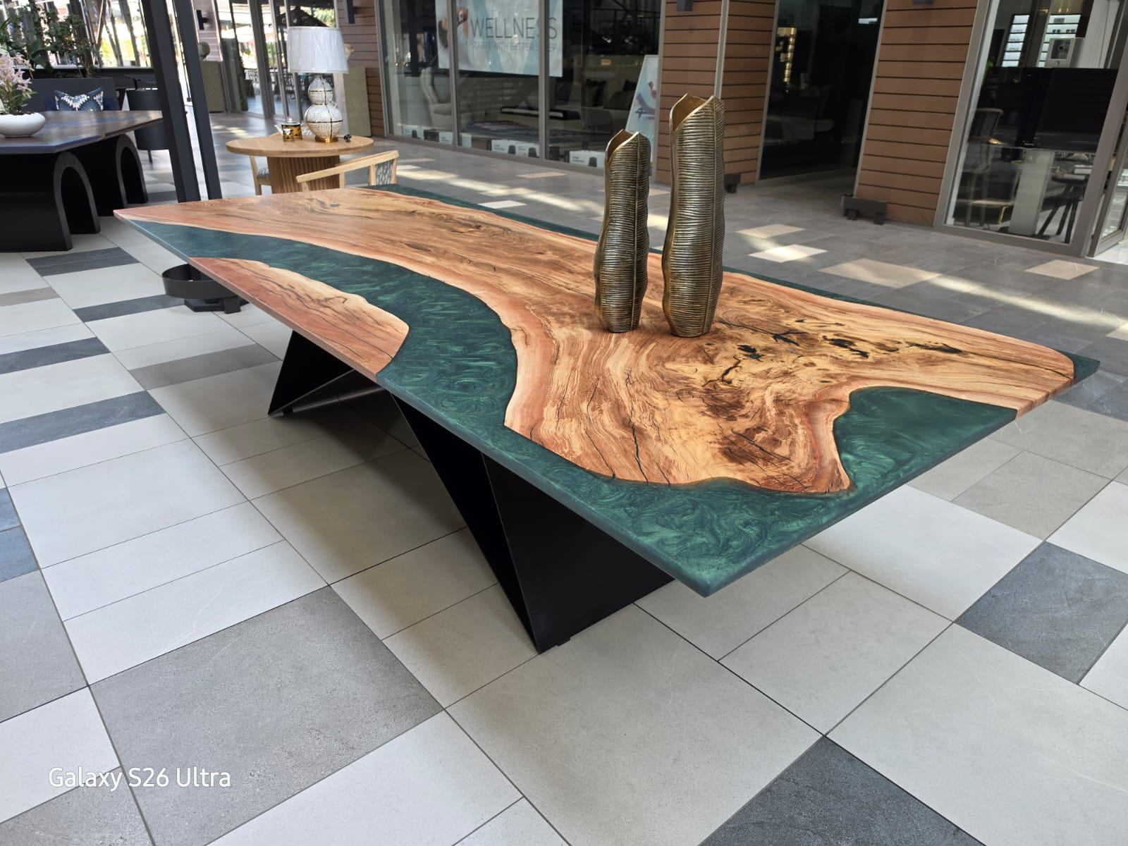 Epoxy river table: a live-edge matumi slab with a green resin river, on a black steel base in the DesignByU showroom