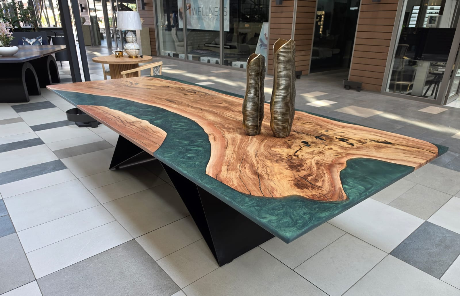 Epoxy river table: a live-edge matumi slab with a green resin river, on a black steel base in the DesignByU showroom